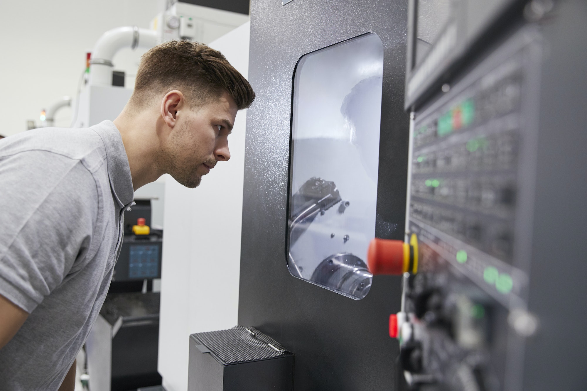 Male Engineer Watching Progress Of CNC Machinery In Factory Male Engineer Watching Progress Of CNC Machinery In Factory